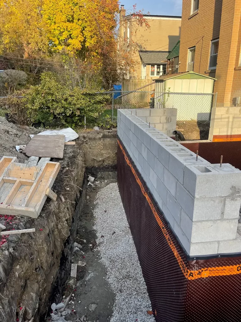 Building Up: Basement Extension in Progress Construction site with new cinder block basement walls and waterproofing over an excavated area, signalling an expansion project