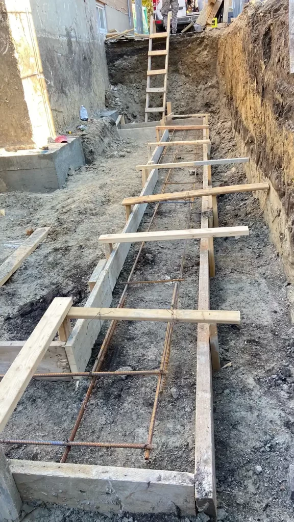 Framework for a Firm Foundation A construction site with wooden forms and rebar grid set up in a foundation pit, prepared for concrete pouring