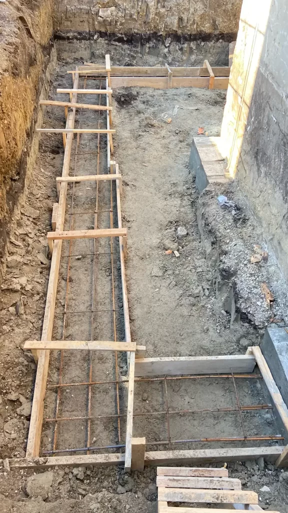 Framework for a Firm Foundation A construction site with wooden forms and rebar grid set up in a foundation pit, prepared for concrete pouring