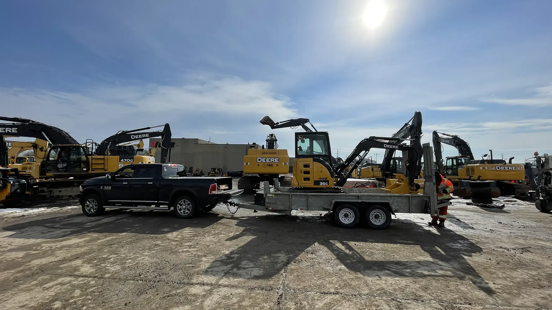 A construction yard with various John Deere excavators and a pickup truck, showcasing the machinery used for heavy-duty building tasks.