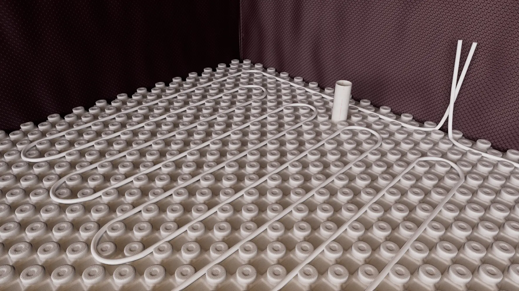 A basement floor being prepared for radiant heating, with a network of white heating pipes on a dimpled plastic insulation membrane, representing the installation of insulation systems and warm floors.