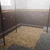 A basement corner with walls covered by a waterproofing membrane and a layer of gravel on the floor, indicating the installation of a waterproofing system during the underpinning process.