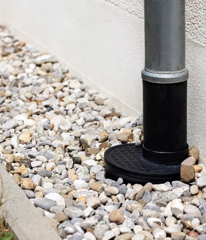Downspout connected to drainage system over gravel bed