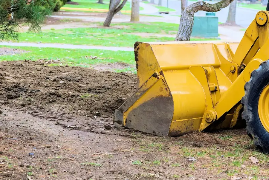 Yellow bulldozer at excavation site with soil pile
