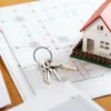 Model house and keys on top of building permit documents and blueprints