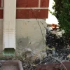 Visible vertical crack in concrete foundation beneath gutter spout