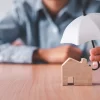 Protecting house with umbrella symbolizing home insurance coverage