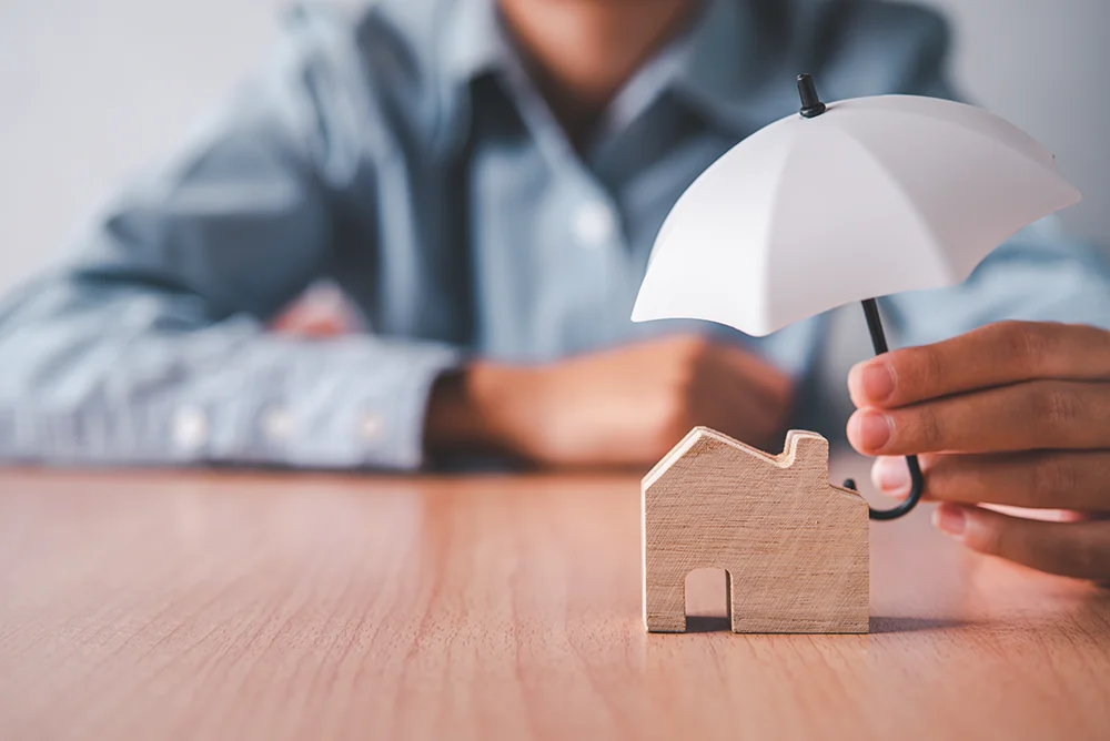Protecting house with umbrella symbolizing home insurance coverage